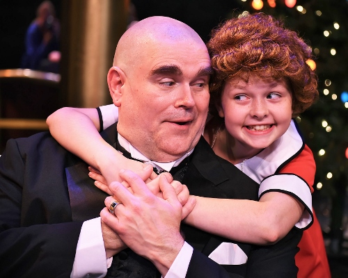 Annie and Daddy Warbucks: Annie (Claire Kauffman) puts her arms around Oliver Warbucks (Ty Stover) in Beef & Boards Dinner Theatre’s production of Annie, now on stage through July 15.