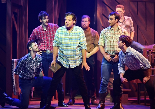 Adam Pontipee (Tony Lawson), center, tells his brothers about a strategy for them to be with the women they love as he sings “Sobbin’ Women” in Seven Brides for Seven Brothers, now on stage at Beef & Boards Dinner Theatre through Oct. 7. This rip-roaring stage version of the classic MGM film is bursting with energetic dance numbers and famous songs including “Wonderful, Wonderful Day,” “Bless Your Beautiful Hide,” and “Goin’ Courting.”